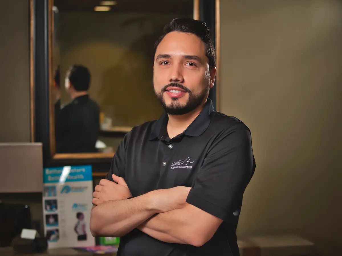 Dr. Guillermo Nazario, chiropractor, standing with arms crossed in his Orlando office